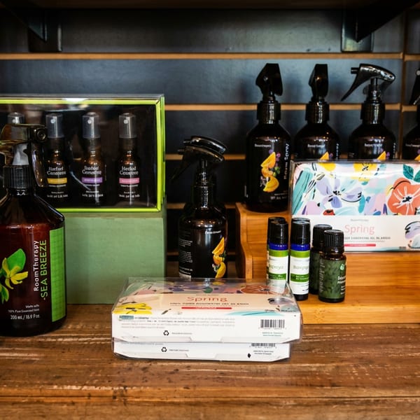 A wooden shelf displays various "Room Therapy" brand room sprays and essential oils.