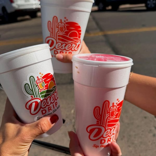 Three Desert Drip dirty sodas being cheersed together in the sun outside on Main Street.