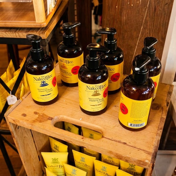 Brown bottles of "The Naked Bee" hand and body lotion on a wooden crate display.
