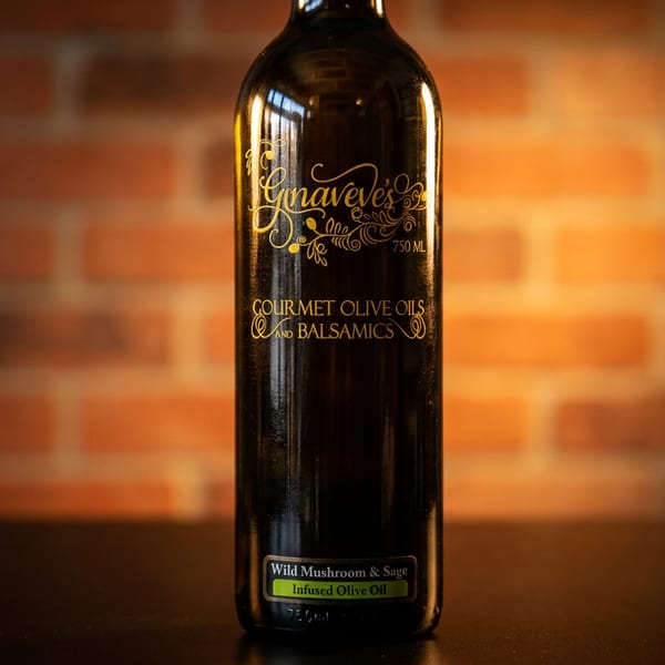 A dark bottle of Gnaveve's Wild Mushroom & Sage Infused Olive Oil against a brick wall.